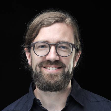 Thomas Immich hat dunkles Haar und einen Vollbart. Er trägt eine Brille. Er lächelt in die Kamera.